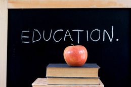 education written above an apple sitting on books